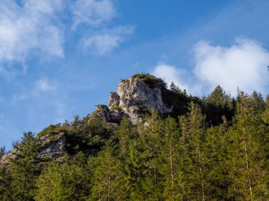 Mavi Gök 'e karşı yükselen kireçtaşı oluşumu dağınık bulutlar ve canlı bahar ormanları