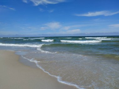 Yumuşak köpüklü dalgalarla el değmemiş terk edilmiş kumsal Açık Mavi Yaz Gökyüzü Altında Sandy Shore 'la buluşuyor