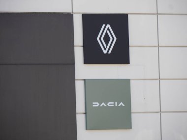 Beyaz Döşeme Arkaplanında Renault ve Dacia Kurumsal Logoları ile Modern Otomotiv Satışı Duvarı Görünümü