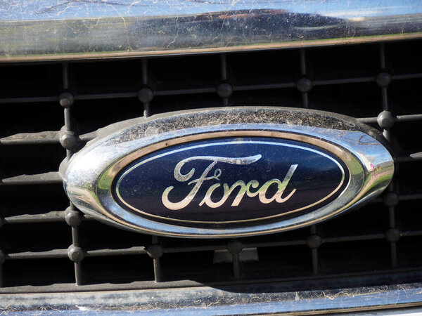 Detailed Closeup of Classic Ford Emblem on Car Grille Showing Iconic Blue Oval Logo