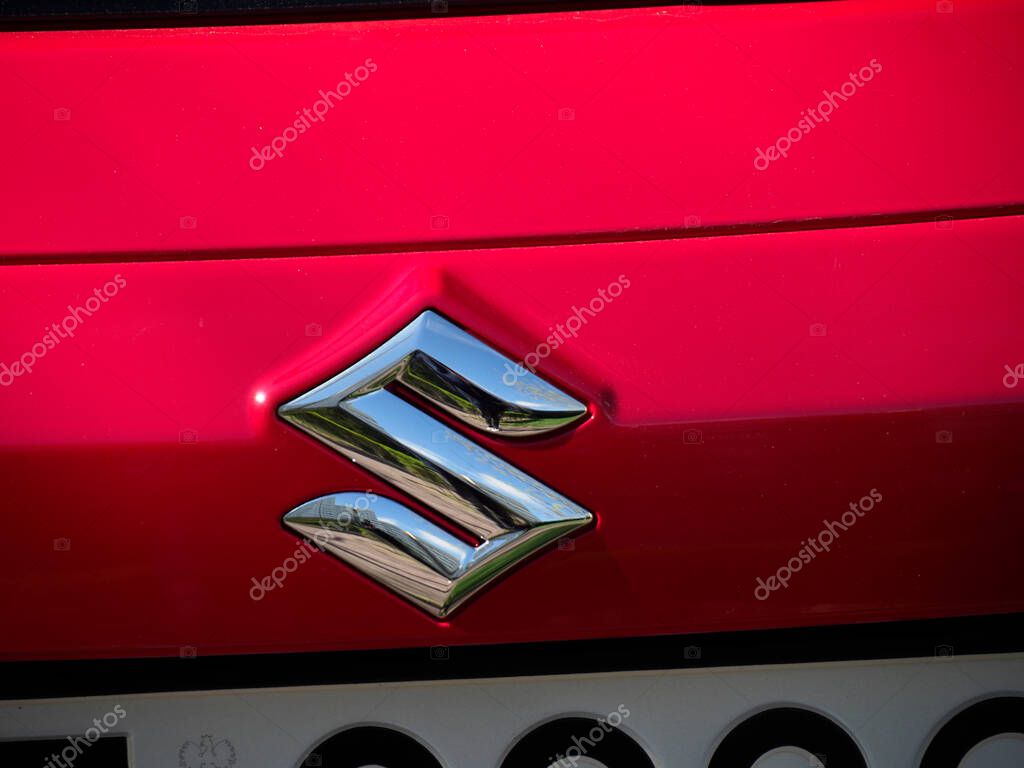 Closeup of Suzuki Logo on Bright Red Car Hood Showing Detailed Metallic Emblem