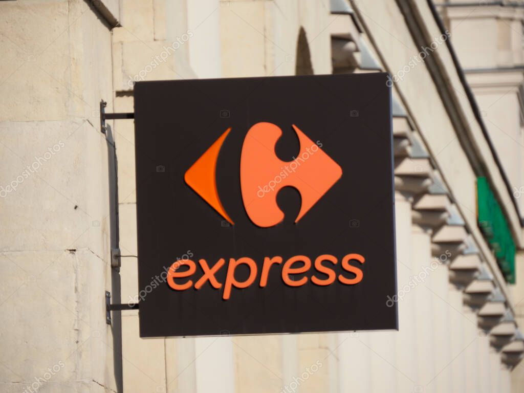 Carrefour Express Store Sign with Orange Logo on Black Background Mounted on Building Wall