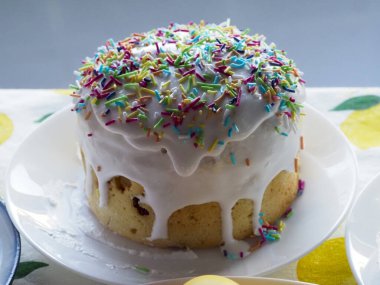 Pürüzsüz beyaz buzlu Paskalya Pastası ve Beyaz Tabakta Renkli Şekerler Yumuşak Bahar Arkaplanına Karşı