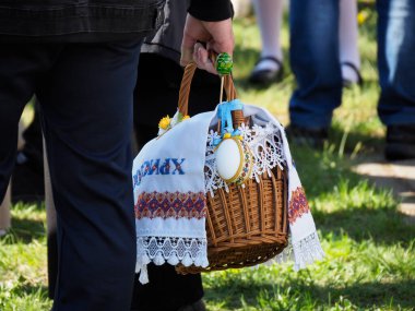 Geleneksel Hasır Paskalya Sepeti taşıyan Beyaz Dantelli ve Dışardaki Kutsama Etkinliği sırasında İşlenmiş Dekorasyonlar