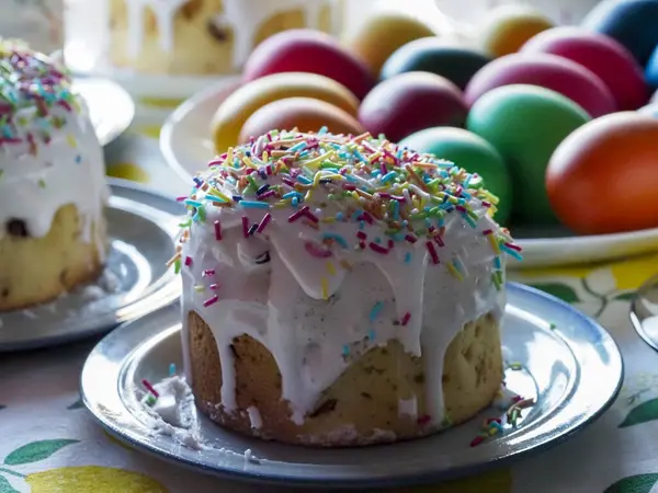 Paskalya Pastası 'nın Beyaz Buzlu ve Gökkuşağı Parlak Masadaki Renkli Yumurtalar' ın yanına serpiştirilmiş.