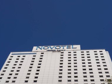 Beyaz Minimalist Mimari Tasarımı ile Modern Novotel Otel Binası Açık Mavi Gökyüzüne Karşı Cephe