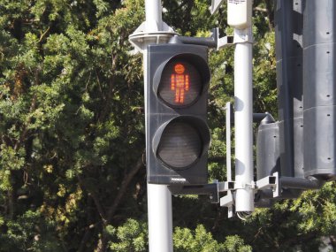 Güneşli bir günde Şehir Trafik Işığı Arkaplanda Bulanık Yeşil Ağaçlarla Kırmızı Durak Sinyali Gösteriyor