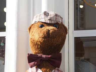 Papyonlu eski oyuncak ayı ve dükkan penceresinden bakan kaptan.