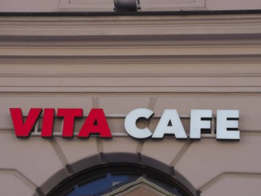 Kentsel Ayarlardaki Bej Bina Cephesinde Parlak Kırmızı ve Beyaz Vita Kafe İmza