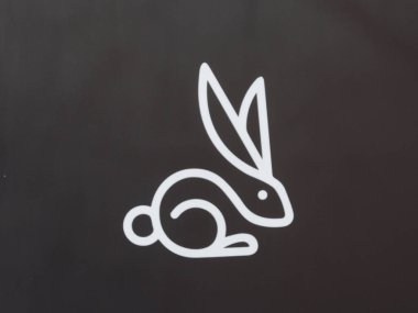 İş Bölgesindeki Modern Şehir Binasının Koyu Gri Duvarında Minimalist Beyaz Tavşan Logosu