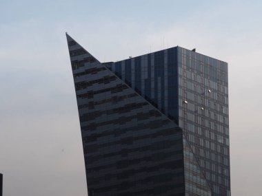 Şehirdeki Bulutlu Gökyüzüne Karşı Ayırt Açılı Çatı Yapılı Modern Geometrik Ofis Kulesi