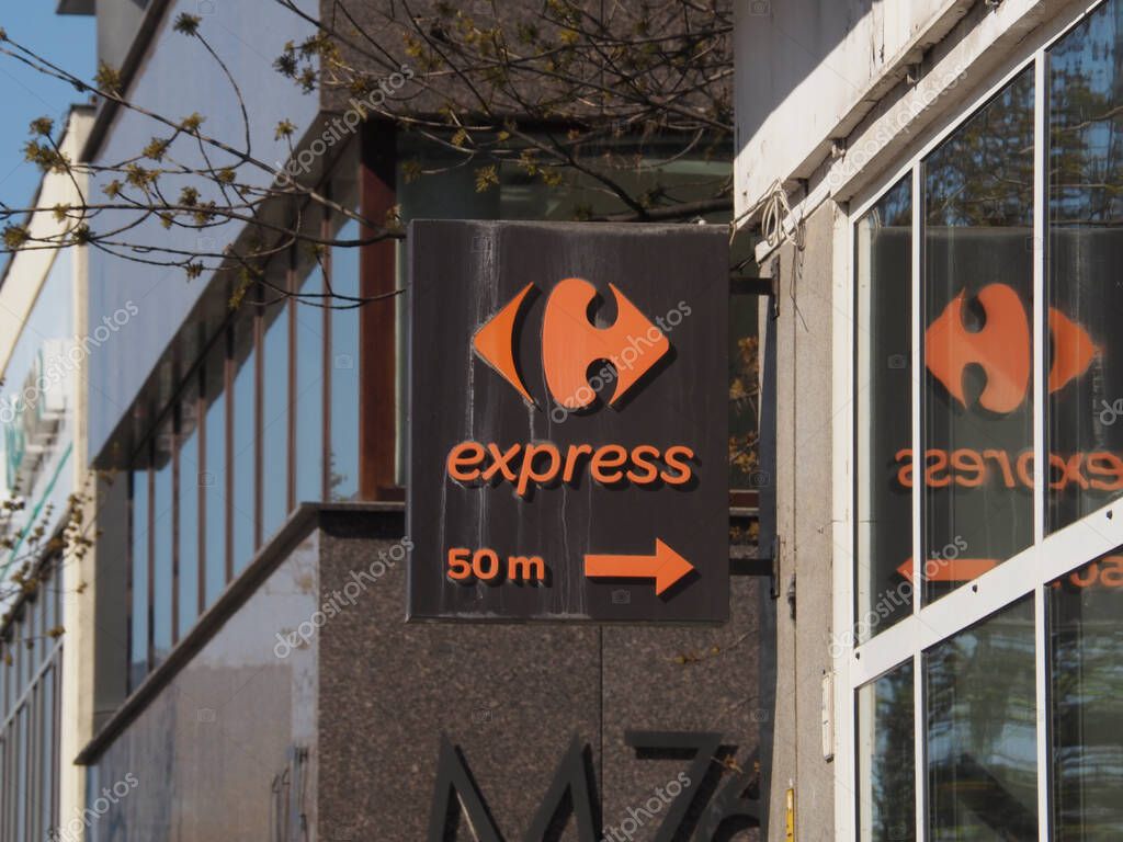 Carrefour Express Grocery Store Sign with Distance Marker on Urban Street Railing in European City
