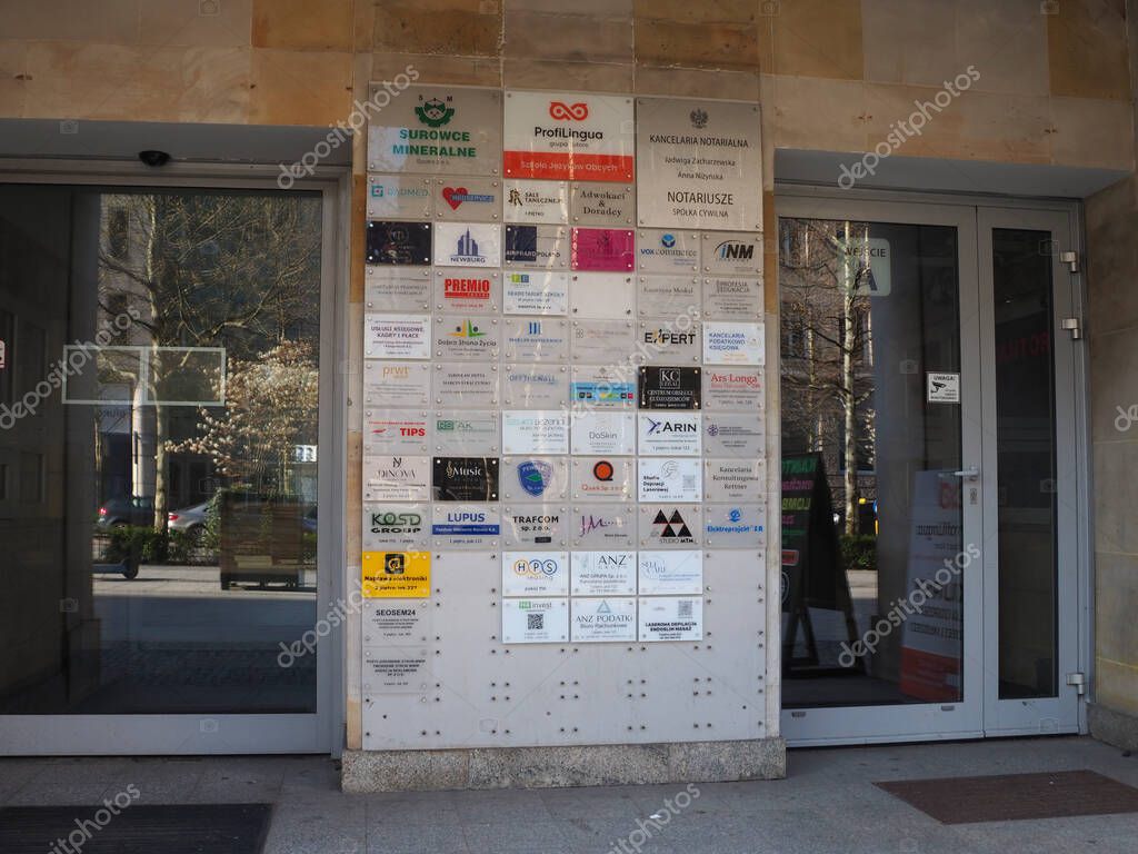 Commercial Building Entrance with Multiple Business Signs and Logos on Beige Stone Facade