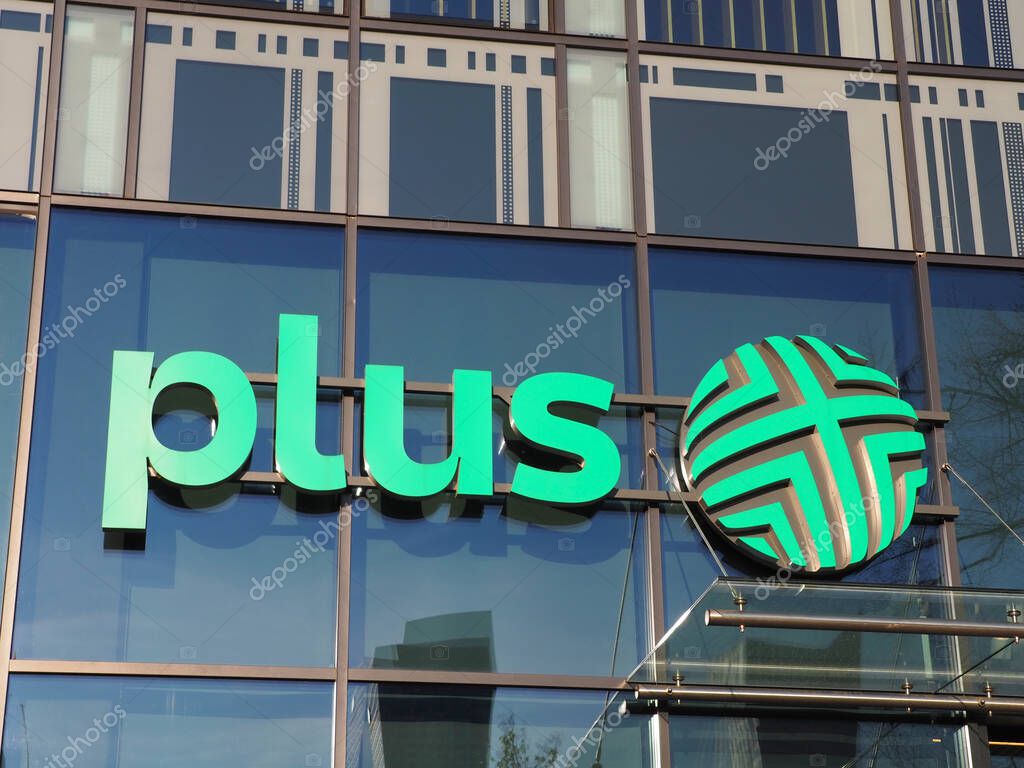 Modern Plus Corporate Logo on Glass Office Building Facade with Stylized Green Ball Symbol Representing Healthcare Company
