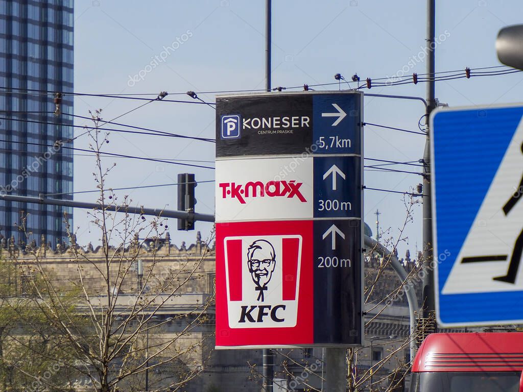 Urban Street Sign with KFC Logo and TK Maxx Direction Indicators Against Modern Buildings