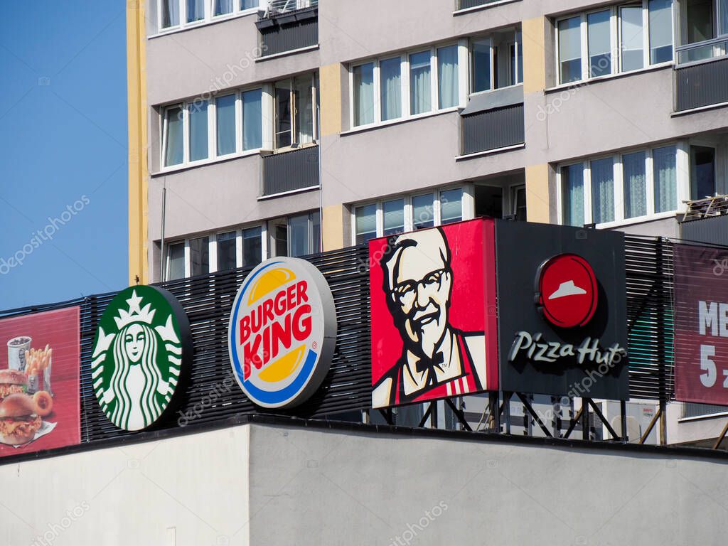 Row of International Fast Food Chain Signs with Starbucks, Burger King and KFC in Warsaw Urban Center