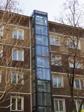 Şehir Merkezinde Cam Asansör Şaftı ve Temiz Mimari Çizgileri olan Modern Apartman Binası