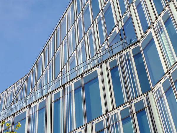 Çağdaş Kentsel İş Bölgesinde Mavi Gökyüzünü Yansıtan Eğri Yüzlü Modern Cam Ofis Binası