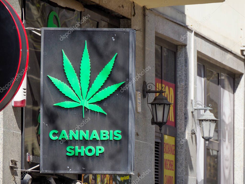 Cannabis Shop Storefront with Bright Green Marijuana Leaf Logo on Modern Urban Building Facade