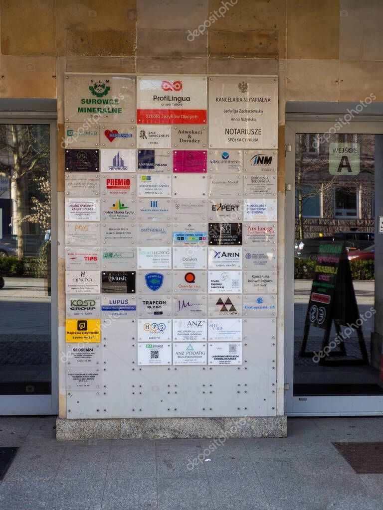 Close-up View of Business Directory Wall with Multiple Company Logos and Signage at Building Entrance in Urban Business District