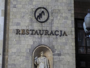 Varşova 'nın eski kasabasında zarif bir tabela ve klasik heykel görünümlü tarihi taş restoran cephesi