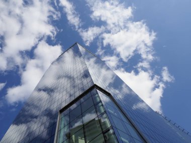 Pofuduk Bulutlu Mavi Gökyüzüne Karşı Noktalı Çatı ile Çarpıcı Modern Cam Gökdelen