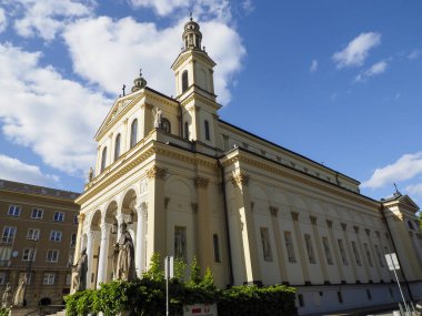 Parlak mavi gökyüzünün altında beyaz bulutlu etkileyici kuleler ve sütunlarla görkemli neoklasik kilise cephesi