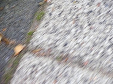 Islak granit kaldırımın detaylı dokusu ve yağmur damlaları ince desenler ve yansımalar yaratıyor.