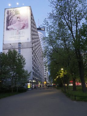 Modern şehir yolu, Varşova 'daki konut binaları ve reklam panoları ile alacakaranlıkta aydınlandı.