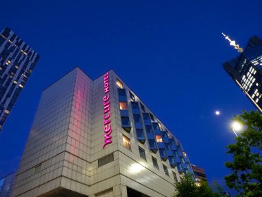 Pembe Dikey Mercure İşareti ve Gece Açısal Mimarisi olan Modern Otel Binası