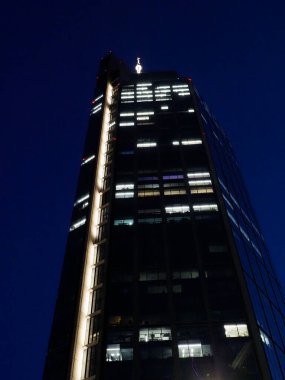 Aydınlatılmış Pencereleri ve Karanlık Gece Gökyüzüne Karşı Düşey Işık Şeridi ile Modern Gökdelen