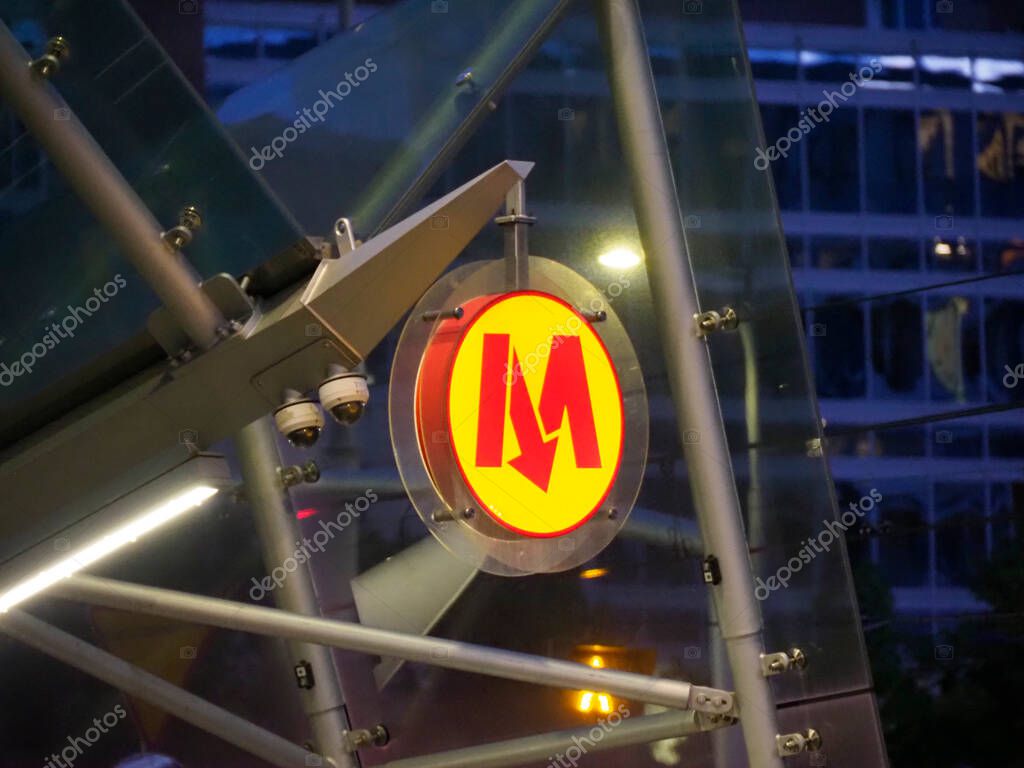 Illuminated Metro Sign at Night with Modern Architecture Structure and Red M Logo on Transport Hub