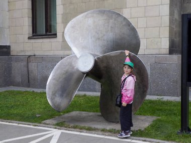 Pembe Ceketli Genç Kız Şehir Parkı 'ndaki Büyük Metal Gemi Pervanesi Heykelini İnceleyecek