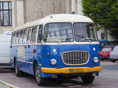 Tarihi binalarla şehir caddesinde klasik mavi ve sarı vintage otobüs, Avrupa 'nın nostaljik toplu taşıma araçlarını yakalıyor.