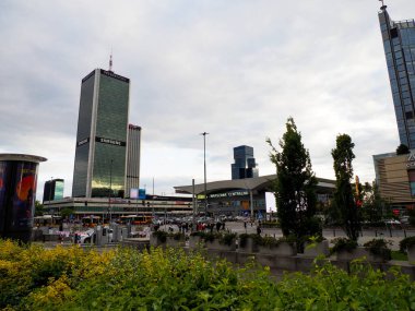 Modern Varşova şehrinin gökdelenleri ve yüksek binaları yemyeşil bitkilerle çevrili, kentsel gelişim ve mimari sergileniyor.