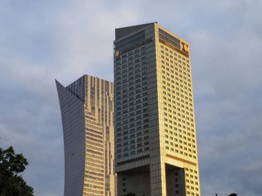 Şehir finans bölgesinde dramatik bulutlu gökyüzü ile modern gökdelenleri aydınlatan altın akşam ışığı