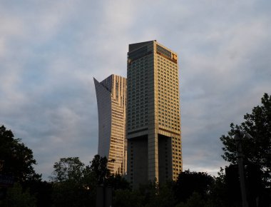 Günbatımını yansıtan modern altın renkli gökdelen finans bölgesinde dramatik bulutlu gökyüzüne karşı