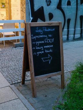 Ahşap restoran menü tahtası, şehir kafesinin yanındaki kaldırımda duran el yazısıyla günlük spesiyaller.