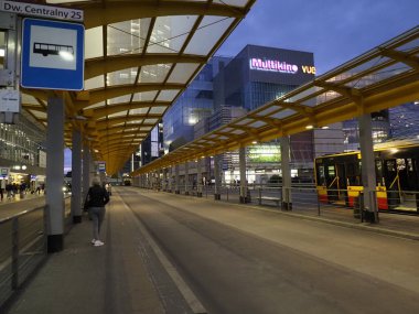 Şehir Ulaşım Merkezinde Sarı Aydınlatılmış Çatı ve Şehir Işıkları ile Gece Boş Otobüs İstasyonu Platformu