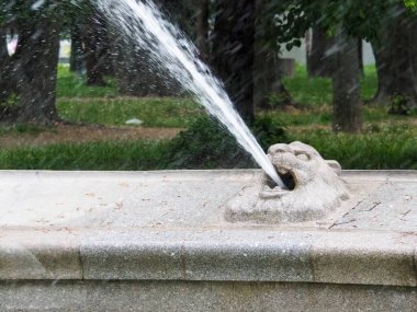 Su fıskiyesinin yakın plan fıskiyesi şehir parkındaki havzaya doğru temiz su püskürtüyor.