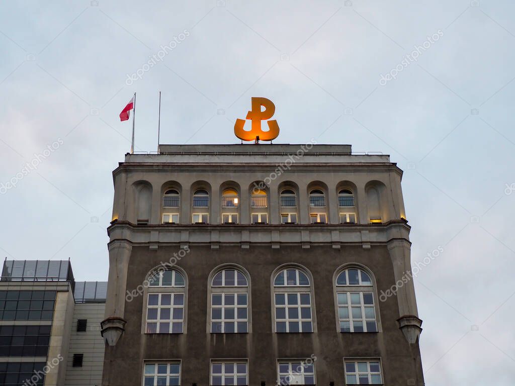 Historic Banking Building with Orange Ampersand Logo and Polish Flag Against Blue Sky in Downtown