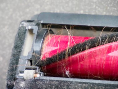 İnsan saçına dolanmış elektrikli süpürge fırçasının detaylı görüntüsü temizlik sırasında günlük saç kaybını gösteriyor.