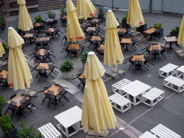 Sarı şemsiyeli ve geometrik desenli boş masalı açık hava restoran terası manzarası.