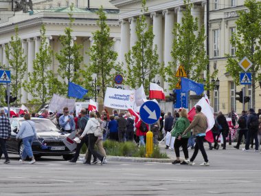 Varşova 'da düzenlenen yürüyüş sırasında arkaplanda tarihi binalar bulunan ulusal bayraklar taşıyan Polonyalı göstericiler