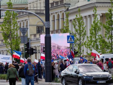 Polonyalı vatanseverler, Varşova şehir merkezinde tarihi mimariyle siyasi gösteri sırasında ulusal bayraklarla yürüyorlar.