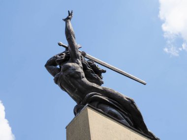 Hareket halindeki dinamik bronz savaşçı heykeli dramatik düşük açılı perspektiften çekilen kılıç kullanıyor.