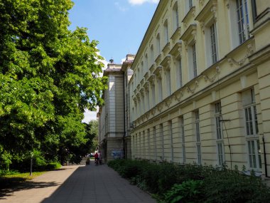 Klasik mimarisi ve peyzajlı zemini olan tarihi kurumsal binanın yanında ağaçlarla kaplı bir patika.