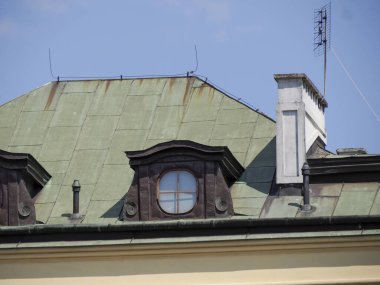 Şehir çatısı perspektifi bulutlu gökyüzü zeminine karşı modern yeşil metal çatı mimarisini gösteriyor