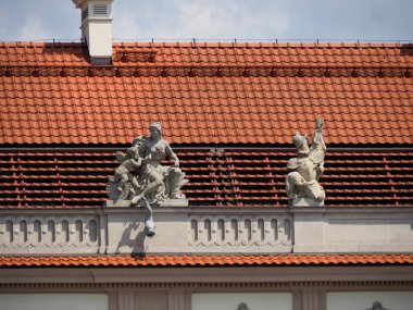 Dekoratif heykelleri olan büyük barok sarayı yan girişi ve kırmızı kiremit çatı kaplaması.