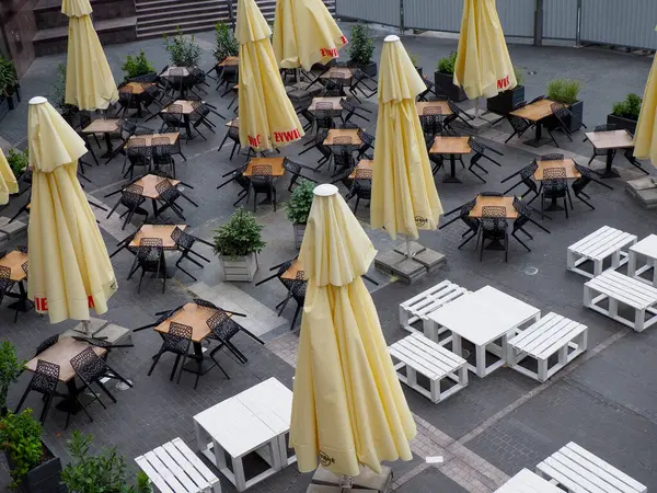 Sarı şemsiyeli ve geometrik desenli boş masalı açık hava restoran terası manzarası.